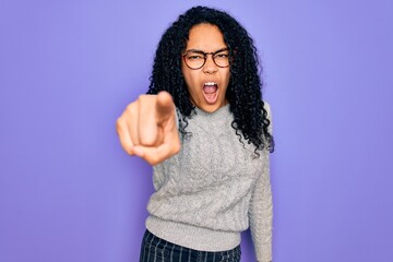 Young african american woman wearing casual sweater and glasses over purple background pointing displeased and frustrated to the camera, angry and furious with you