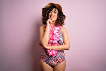 Young beautiful arab woman on vacation wearing swimsuit and hawaiian lei flowers looking confident at the camera with smile with crossed arms and hand raised on chin. Thinking positive.