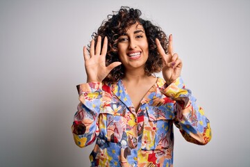 Young beautiful curly arab woman wearing floral colorful shirt standing over white background showing and pointing up with fingers number seven while smiling confident and happy.