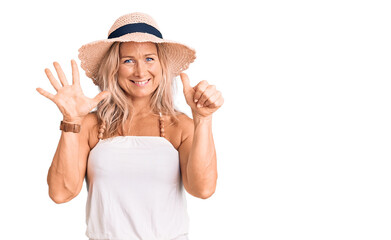 Obraz na płótnie Canvas Middle age fit blonde woman wearing summer hat showing and pointing up with fingers number six while smiling confident and happy.