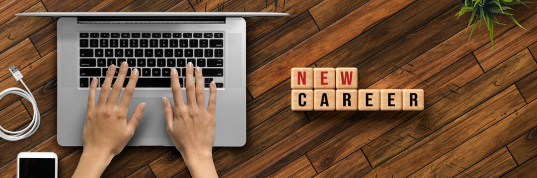 hand is typing on a computer keyboard and cubes with message NEW CAREER on wooden background