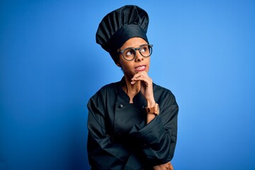 Young african american chef woman wearing cooker uniform and hat over blue background Thinking worried about a question, concerned and nervous with hand on chin
