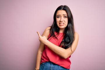 Young brunette woman wearing casual summer shirt over pink isolated background Pointing aside worried and nervous with forefinger, concerned and surprised expression