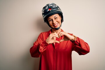 Middle age motorcyclist woman wearing motorcycle helmet over isolated white background smiling in love doing heart symbol shape with hands. Romantic concept.