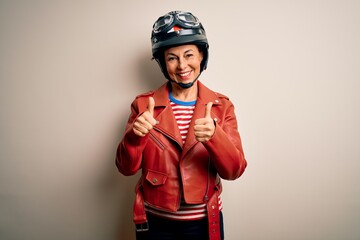 Middle age motorcyclist woman wearing motorcycle helmet and jacket over white background success...