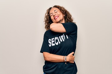 Middle age beautiful guard woman wearing security t-shirt uniform over white background hugging...
