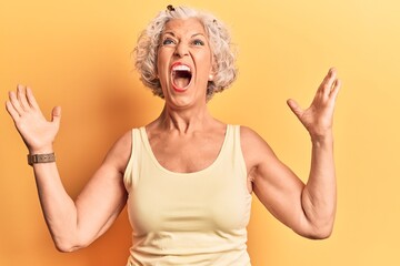 Senior grey-haired woman wearing casual clothes crazy and mad shouting and yelling with aggressive...