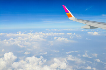 A wing of plane in the sky. Beautiful view of blue sky above the white clouds from airplane window.