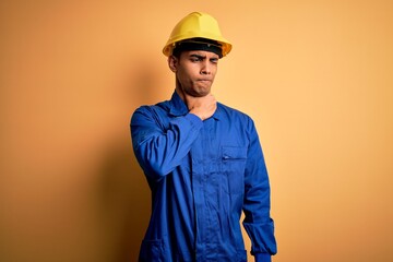 Young handsome african american worker man wearing blue uniform and security helmet Touching painful neck, sore throat for flu, clod and infection