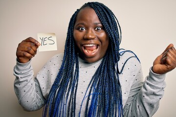 Young african american plus size woman with braids holding reminder paper with yes message...