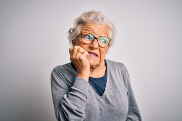 Senior beautiful grey-haired woman wearing casual sweater and glasses over white background looking stressed and nervous with hands on mouth biting nails. Anxiety problem.