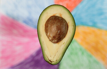 Half avocado with a bone on a colorful background. Close-up.