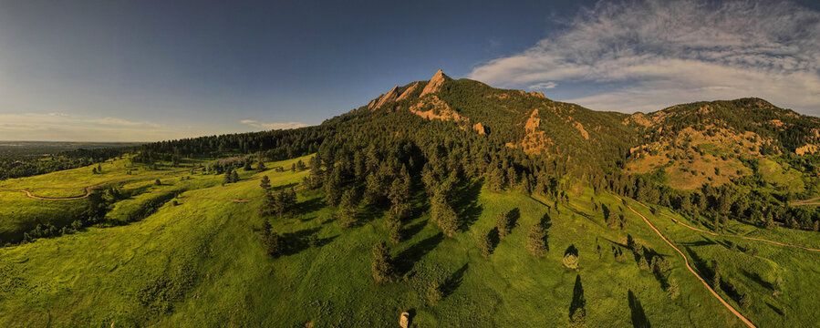 panorama of the boulder flatiron mountains during sunrise against blue sky background with clouds