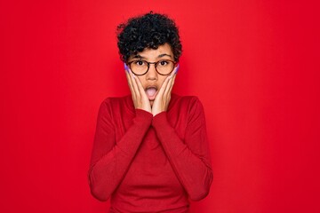 Fototapeta na wymiar Young beautiful african american afro woman wearing turtleneck sweater and glasses afraid and shocked, surprise and amazed expression with hands on face