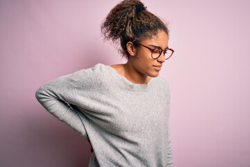 Young beautiful african american girl wearing sweater and glasses over pink background Suffering of backache, touching back with hand, muscular pain