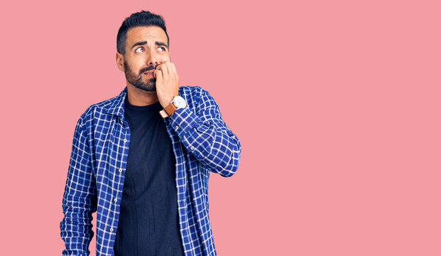 Young hispanic man wearing casual clothes looking stressed and nervous with hands on mouth biting nails. anxiety problem.