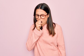 Young beautiful brunette woman wearing casual sweater and glasses over pink background feeling...
