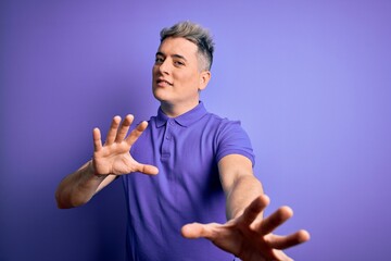 Young handsome modern man wearing casual purple t-shirt over isolated background afraid and terrified with fear expression stop gesture with hands, shouting in shock. Panic concept.