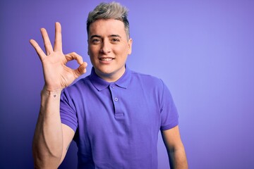 Young handsome modern man wearing casual purple t-shirt over isolated background smiling positive doing ok sign with hand and fingers. Successful expression.