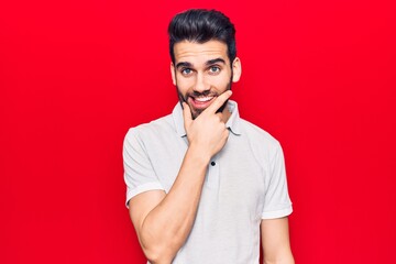 Young handsome man with beard wearing casual polo looking confident at the camera smiling with crossed arms and hand raised on chin. thinking positive.