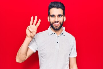 Young handsome man with beard wearing casual polo showing and pointing up with fingers number three while smiling confident and happy.