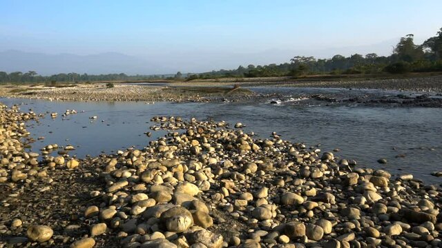 Murti river in the morning, riverbed in foreground with flowing water and stones. Scenic beauty of Dooars landscape, West Bengal, India