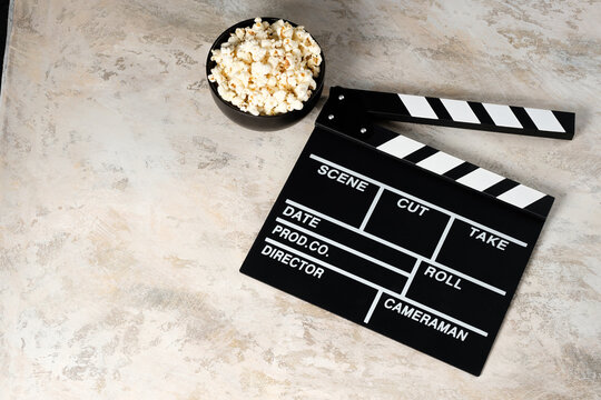 Clapper board with popcorn. Movie concept. Clapperboard on a textural background. Close-up. Copy space.