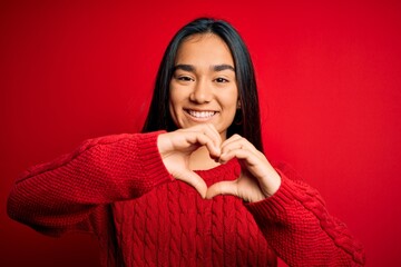 Young beautiful asian woman wearing casual sweater standing over isolated red background smiling in...
