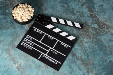 Clapper board with popcorn. Movie concept. Clapperboard on a textural background. Close-up. Copy...
