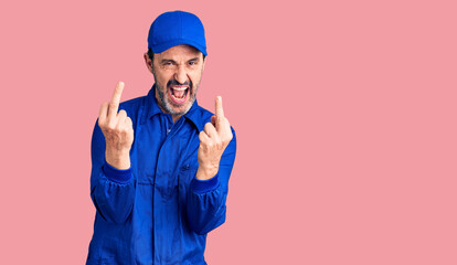 Naklejka premium Middle age handsome man wearing mechanic uniform showing middle finger doing fuck you bad expression, provocation and rude attitude. screaming excited