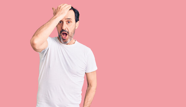 Middle age handsome man wearing casual t-shirt surprised with hand on head for mistake, remember error. forgot, bad memory concept.