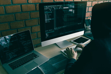 Hacker in the hood working with computer with hacking breaking into data servers.