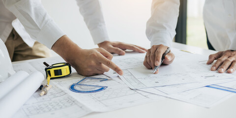 Two partnership architects or engineering working with blueprints and discussing project together...