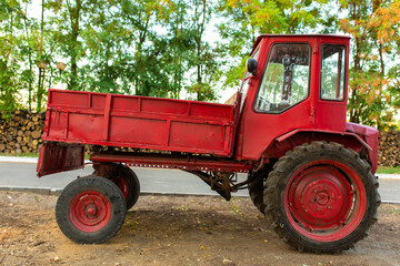 Obraz premium Red tractor with a trunk in front. Transport vehicles in the village