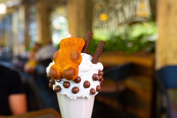 Cool milkshake with cookies and chocolate balls. Milkshake in a glass beaker on a table on a street platform in a cafe. Refreshing summer drinks