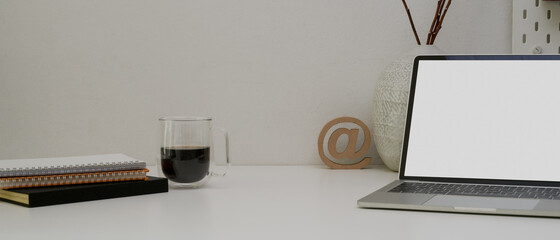 Modern office desk with copy space, mock-up laptop, schedule books, coffee cup and decorations