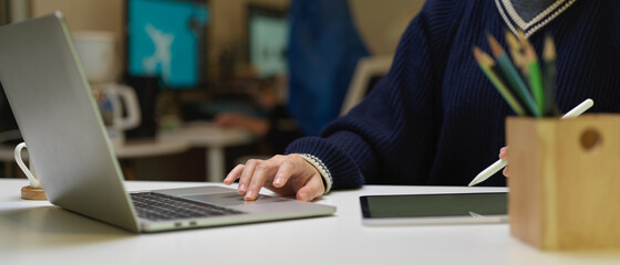 Female graphic designer working with digital tablet and laptop on white office desk