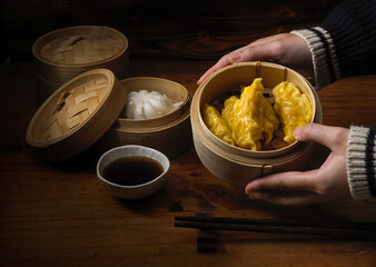 Hands holding steamed dumplings serving on bamboo seamer in Chinese restaurants