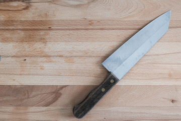 Knife on brown wooden cutting board on kitchen background