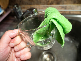 a woman washes a transparent mug at home in the kitchen in the sink close up