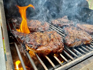 ribeye steaks grilling on an open flame in a grill