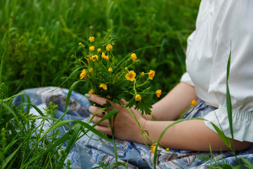 Girl in a field with a bunch of wild flowers in their hands.