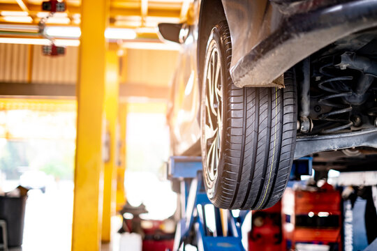 car automobile mechanic working on repairing the wheel tire of vehicle, taking car in for service workshop for male car mechanic fixing problems replacing broken parts of using tools and equipment