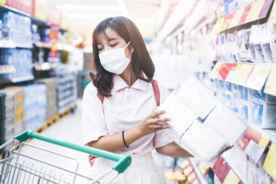 beautiful asian girl wearing facemask protection coronavirus covid-19, shopping trolley buying food water grocery shopping at super store market stocking resource for world pandemic home quarantine
