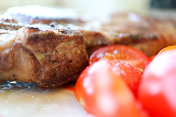 delicious grilled juicy pork meat steak with vegetables cherry tomatoes close up