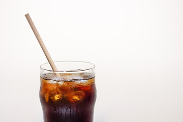 Coffee with ice in a glass cup with tube on a white background, a copy of the space