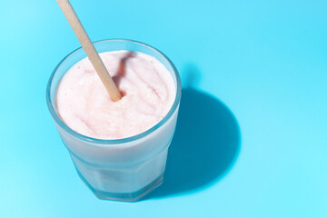 Strawberry milkshake with a tube on blue background, a copy of the space