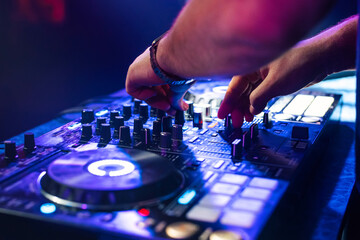 DJ hands mix music on a mixing Board in a nightclub