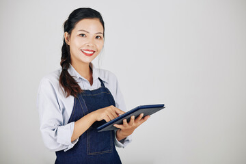 Portrait of young female coffeeshop owner using application on tablet computer when accepting orders from customers