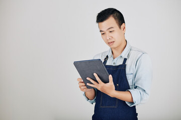 Cafe worker reading orders from customers on tablet computer, isolated on grey